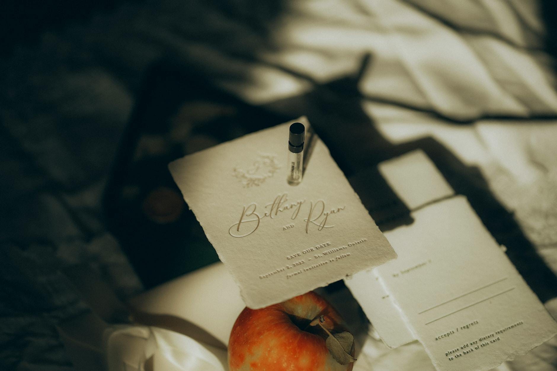 Eleganckie zaproszenie ślubne w aranżacji flat lay z jabłkiem i perfumami