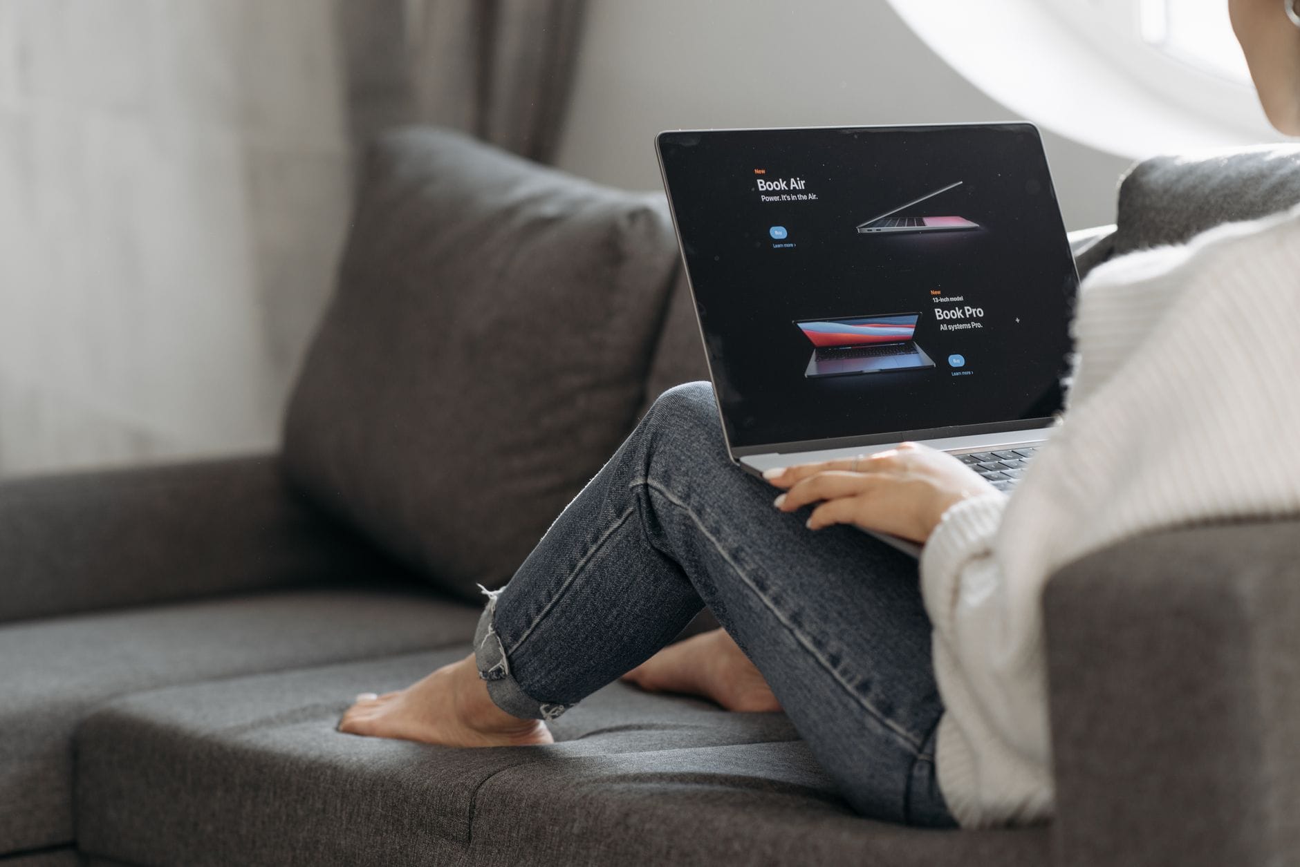 Kobieta na kanapie przegląda oferty laptopów w internecie