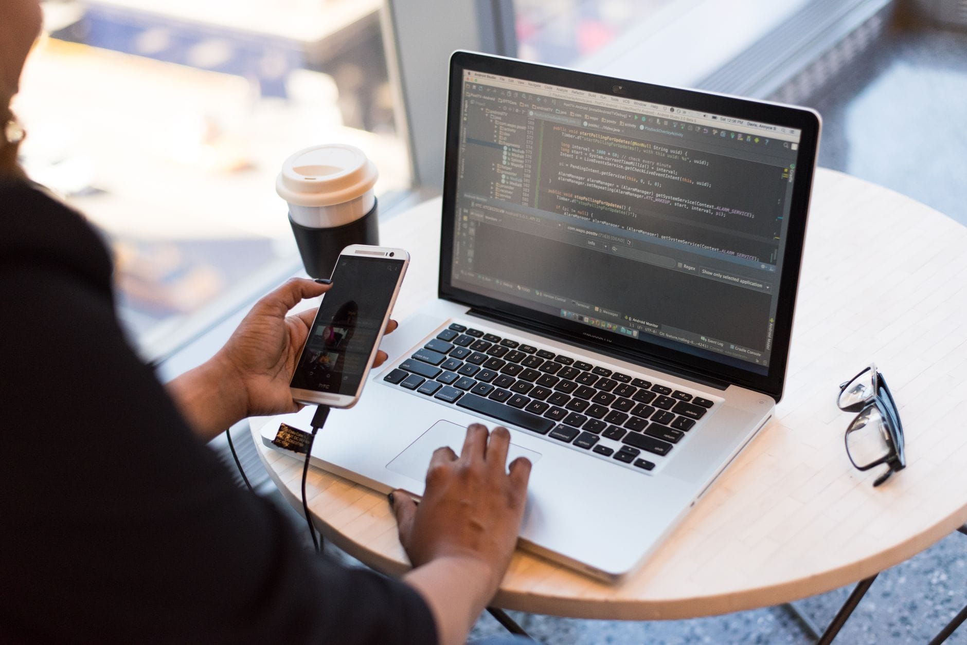 Jak ograniczyć dostęp do produkcji w DevOps, nie blokując pracy zespołom developerskim Programista DevOps zdalnie pracuje na laptopie, trzymając telefon