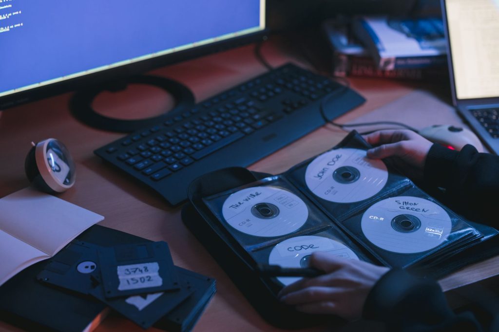 Zbliżenie na płyty CD i dyski na biurku oraz dłonie użytkownika